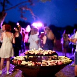 Invités en soirée autour d'un braséro garni de grillades